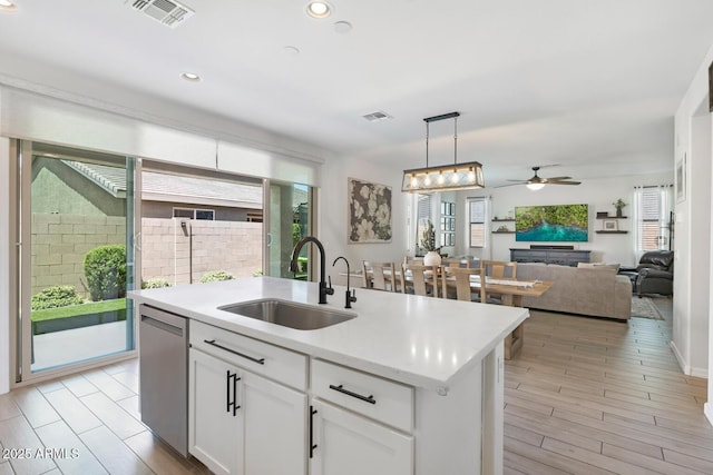 kitchen with a sink, dishwasher, ceiling fan, light countertops, and white cabinetry