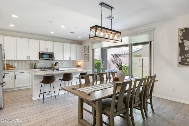 dining area with light wood-type flooring, recessed lighting, and baseboards