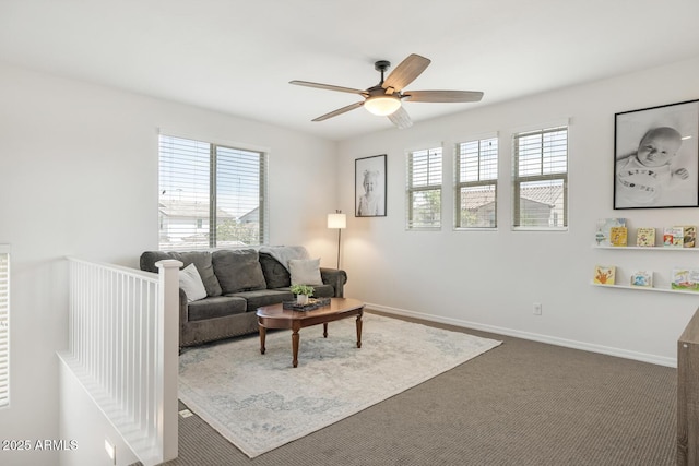 living room with healthy amount of natural light, ceiling fan, dark colored carpet, and baseboards