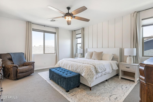 bedroom with multiple windows, light colored carpet, baseboards, and a ceiling fan