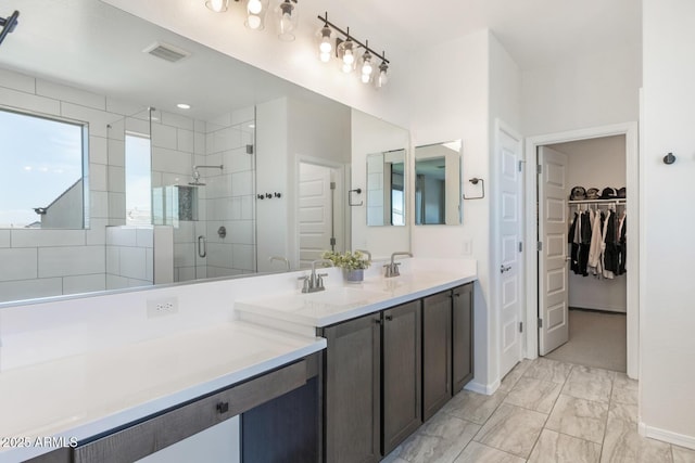 full bath featuring a stall shower, marble finish flooring, vanity, a walk in closet, and baseboards
