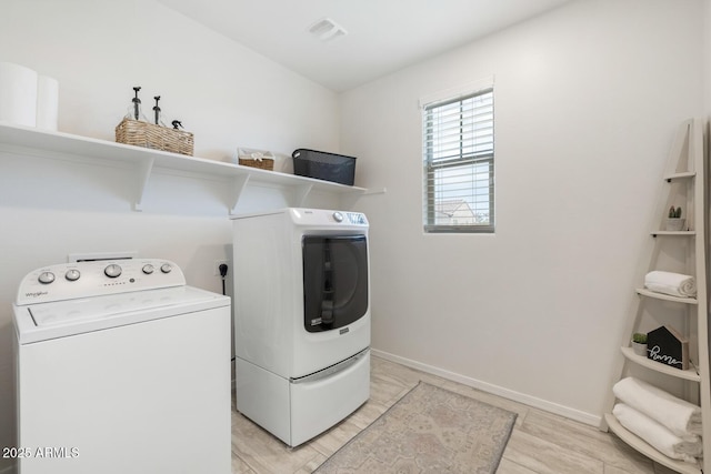 washroom featuring washer and dryer, light wood-style flooring, and baseboards