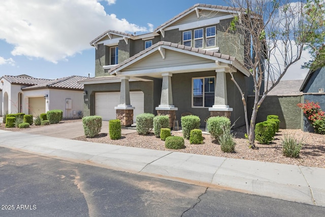 craftsman inspired home with a tile roof, concrete driveway, covered porch, stucco siding, and a garage