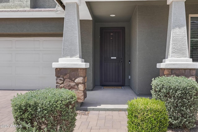 doorway to property featuring stucco siding and an attached garage