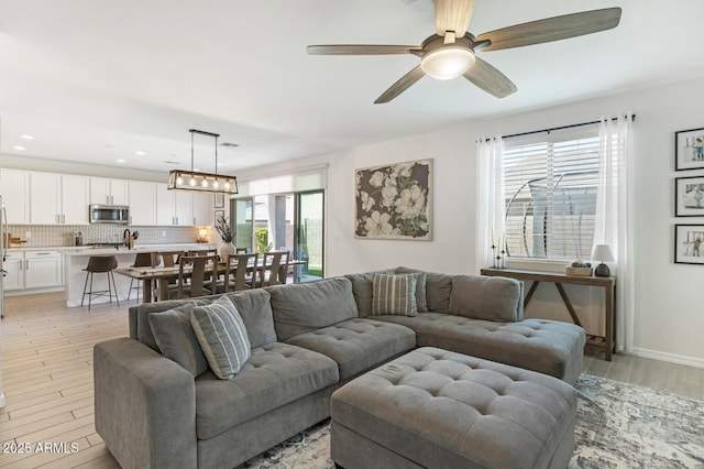 living area with light wood finished floors, a ceiling fan, and recessed lighting