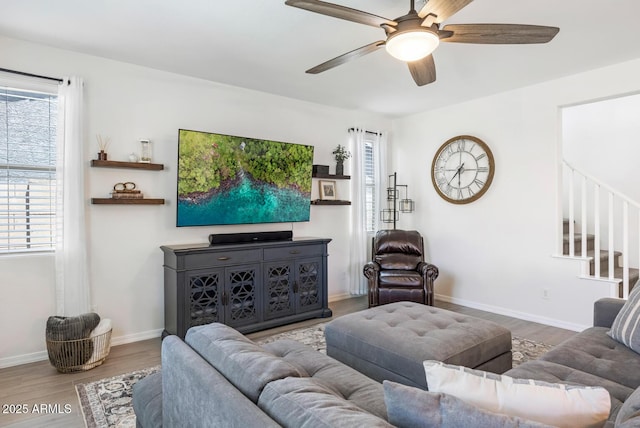 living area with wood finished floors, ceiling fan, stairway, and baseboards