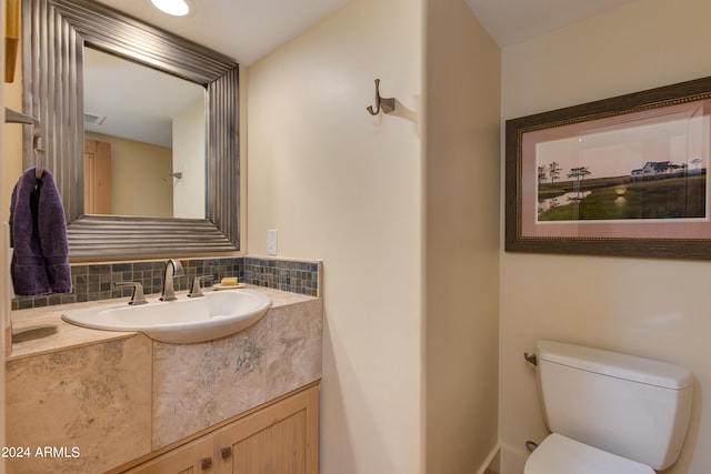 bathroom featuring vanity, toilet, and tasteful backsplash