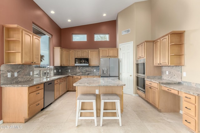 kitchen featuring sink, a kitchen island, stainless steel appliances, a kitchen bar, and light brown cabinets