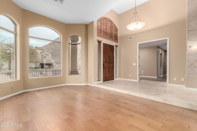 empty room featuring light hardwood / wood-style floors and a towering ceiling