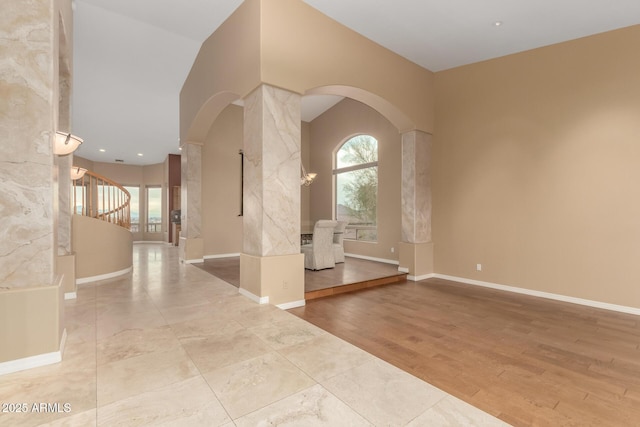 spare room with light hardwood / wood-style flooring and decorative columns