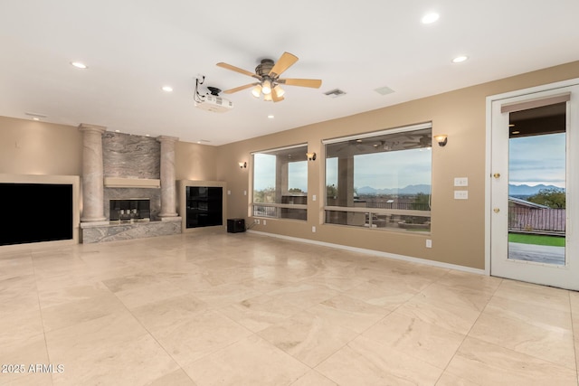 unfurnished living room featuring ceiling fan and a stone fireplace