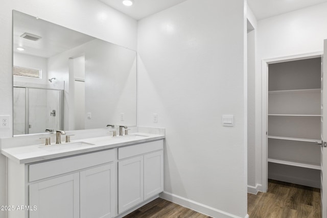 bathroom with an enclosed shower, vanity, and wood-type flooring