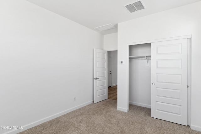 unfurnished bedroom with light colored carpet and a closet