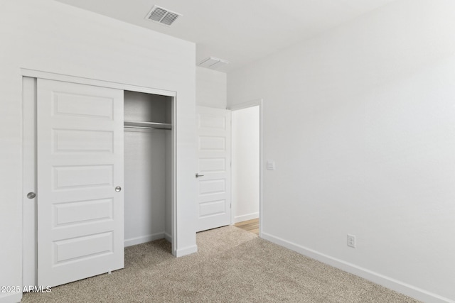 unfurnished bedroom featuring light carpet and a closet