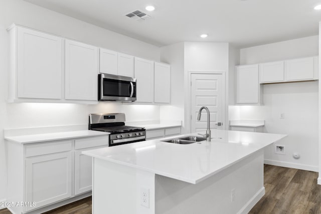 kitchen featuring sink, stainless steel appliances, white cabinets, and a center island with sink