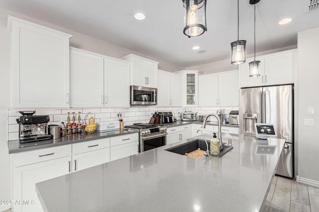 kitchen featuring pendant lighting, sink, appliances with stainless steel finishes, white cabinetry, and tasteful backsplash