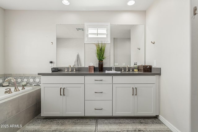 bathroom featuring tiled tub and vanity