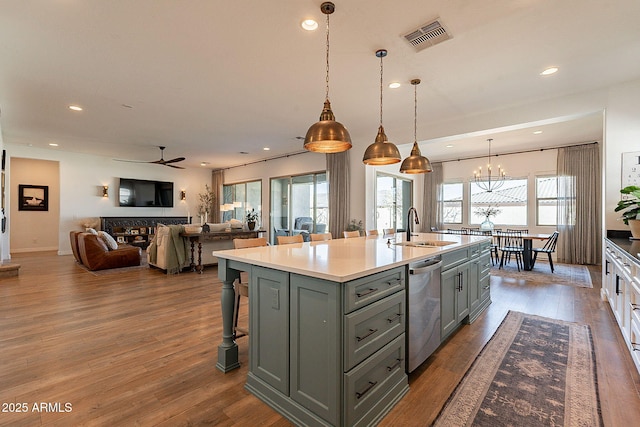 kitchen featuring gray cabinets, visible vents, stainless steel dishwasher, a sink, and wood finished floors