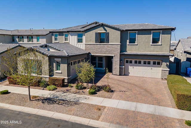 view of front of home featuring decorative driveway, stucco siding, an attached garage, a residential view, and stone siding