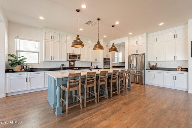 kitchen featuring stainless steel appliances, light wood finished floors, visible vents, and white cabinets