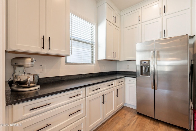 kitchen featuring dark countertops, white cabinets, stainless steel fridge, and light wood-style flooring