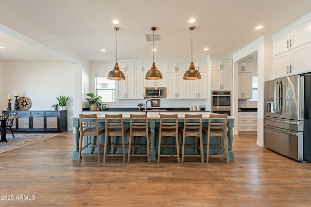 kitchen with stainless steel appliances, visible vents, a sink, and wood finished floors