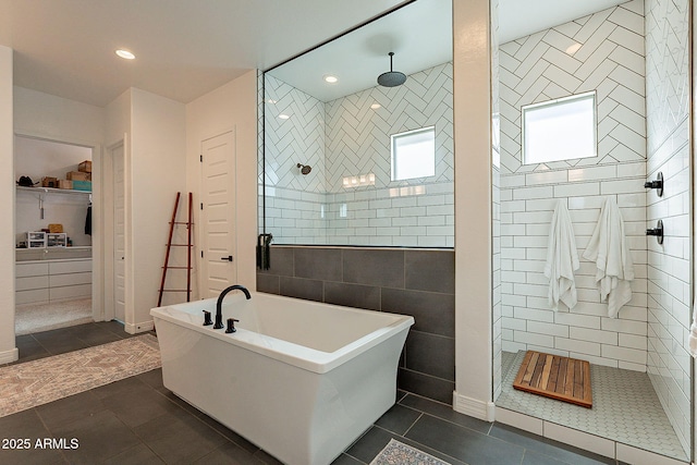 bathroom featuring a walk in shower, a freestanding bath, tile patterned flooring, and tile walls