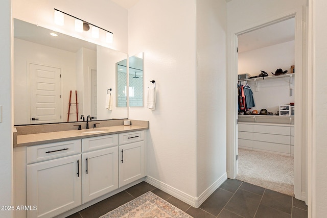 bathroom featuring baseboards, tile patterned flooring, vanity, and a walk in closet