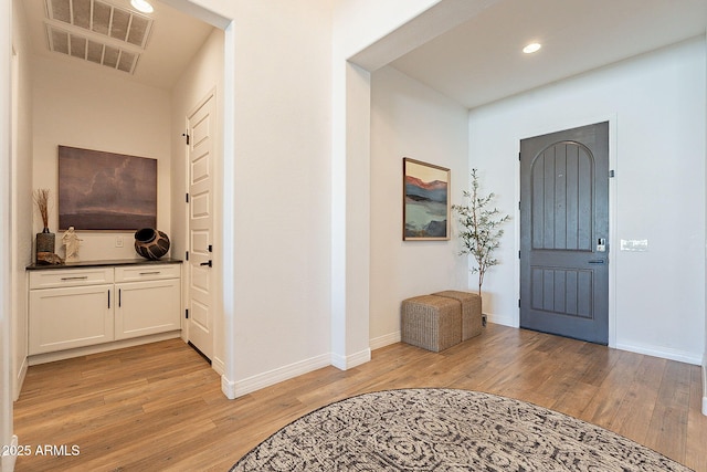 foyer featuring baseboards, visible vents, and light wood finished floors