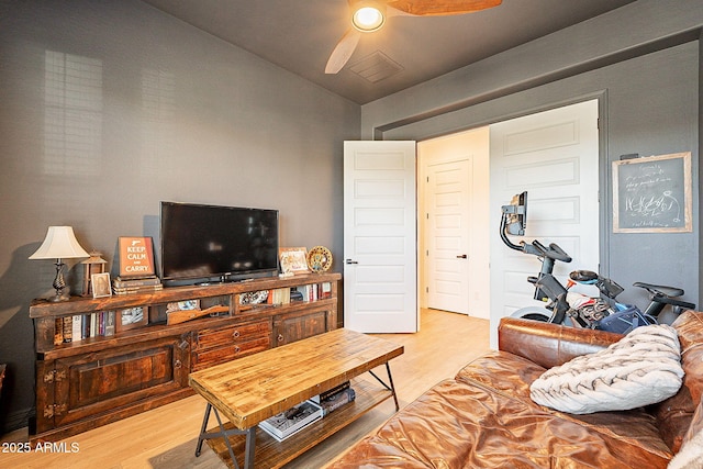 living area with a ceiling fan, light wood-type flooring, and vaulted ceiling