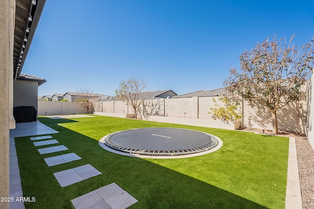 view of yard with a fenced backyard, a trampoline, and a patio