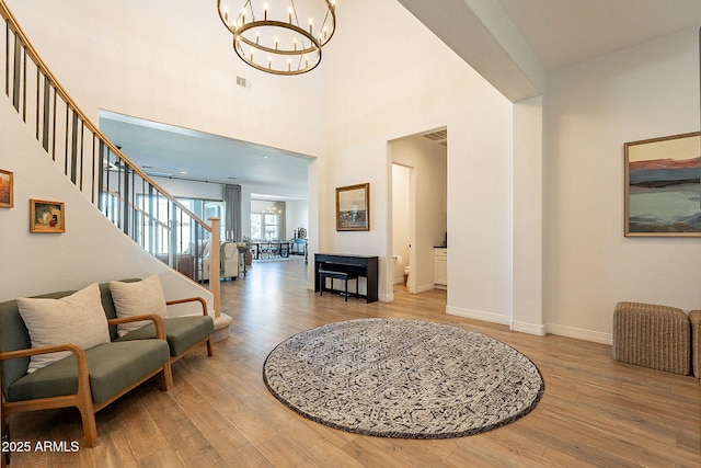 entryway featuring baseboards, visible vents, stairway, wood finished floors, and a chandelier