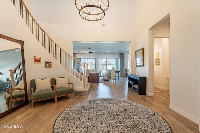 entryway featuring baseboards, stairway, a towering ceiling, and wood finished floors