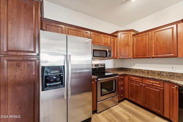 kitchen featuring stainless steel appliances, light hardwood / wood-style floors, and dark stone countertops