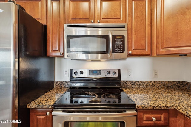 kitchen featuring stainless steel appliances and dark stone counters