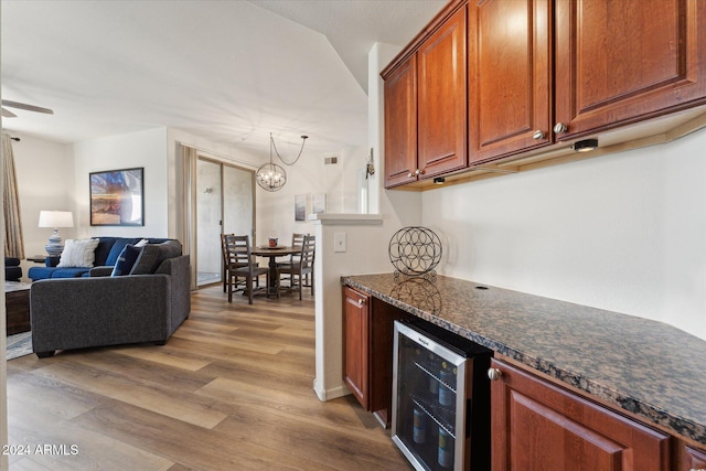 kitchen featuring ceiling fan with notable chandelier, dark stone countertops, wine cooler, and light hardwood / wood-style flooring