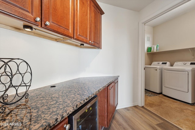 clothes washing area with bar area, washing machine and dryer, beverage cooler, and light hardwood / wood-style flooring