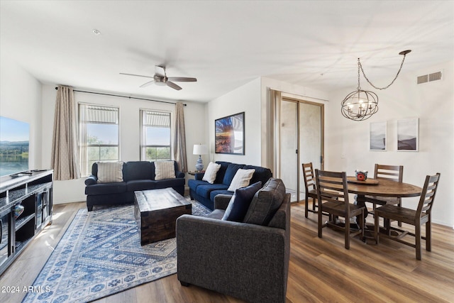 living room with ceiling fan with notable chandelier and hardwood / wood-style flooring