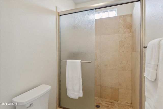 bathroom with a shower with shower door and toilet