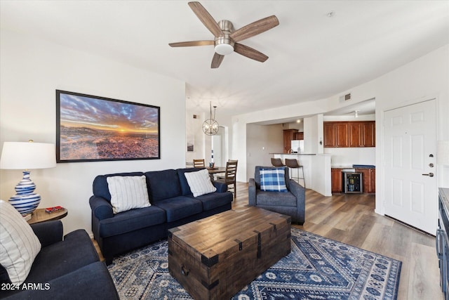 living room featuring ceiling fan with notable chandelier and dark wood-type flooring