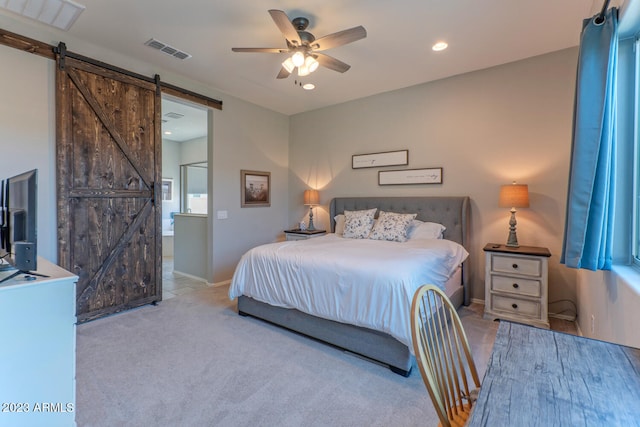 carpeted bedroom with ensuite bathroom, ceiling fan, and a barn door