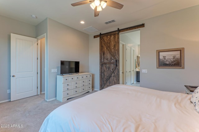 bedroom with ceiling fan, light colored carpet, and a barn door