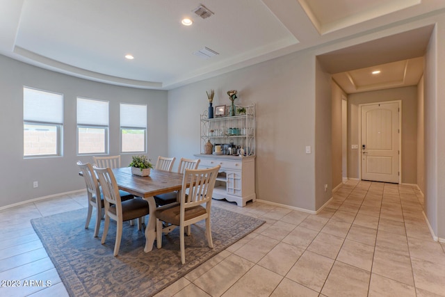 tiled dining space with a raised ceiling