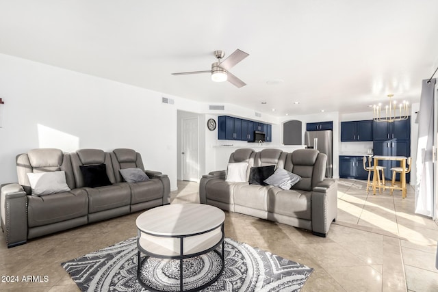 tiled living room featuring ceiling fan with notable chandelier