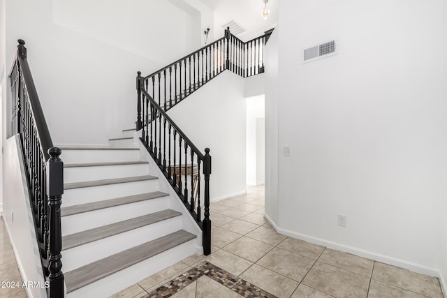 stairs with tile patterned floors and a high ceiling