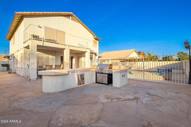 view of patio / terrace featuring a balcony, an outdoor kitchen, and grilling area