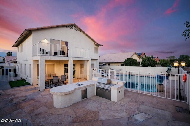 patio terrace at dusk with a fenced in pool, a balcony, area for grilling, and grilling area