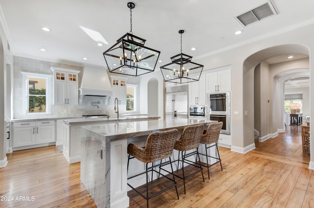 10191 E Diamond Rim Dr Unit 2122, Scottsdale, AZ 85255 - kitchen with custom exhaust hood, built in appliances, a large island, arched walkways, and crown molding