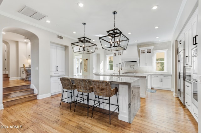 kitchen with a large island, white cabinets, and a healthy amount of sunlight