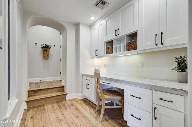 home office with built in desk and light hardwood / wood-style floors